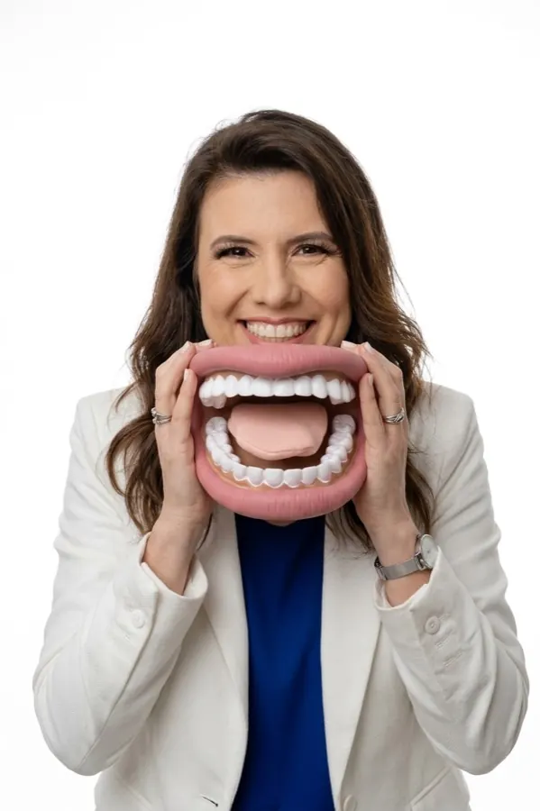 Dra. Renata Bertagnoli segurando um modelo anatômico de arcada dentária usado em fonoaudiologia